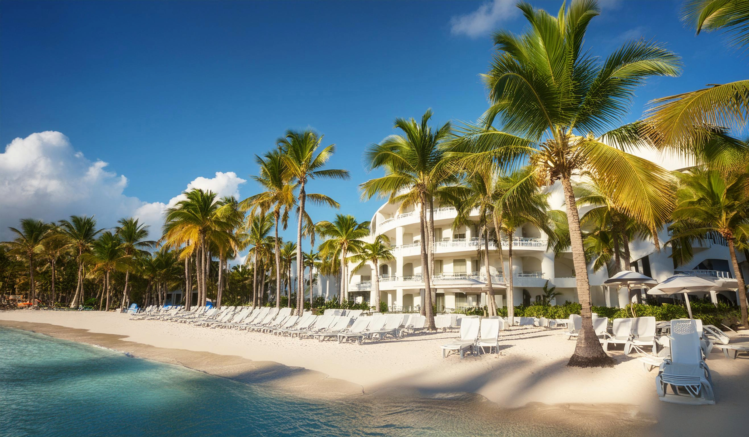 hotel-am-strand-der-dominikanischen-republik-mit-palmen-und-sonnenliegen